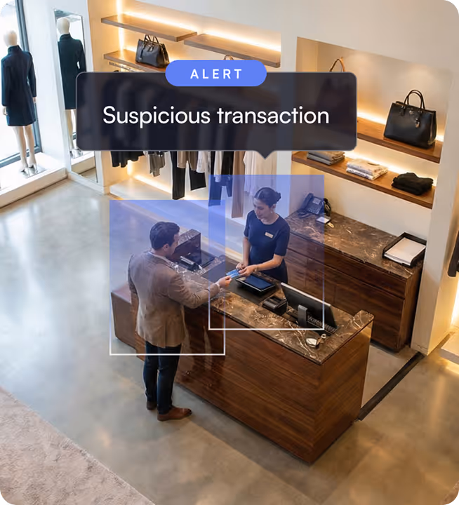 Man making a payment at a retail store counter with a female cashier and an alert message above reading 'Suspicious transaction'.