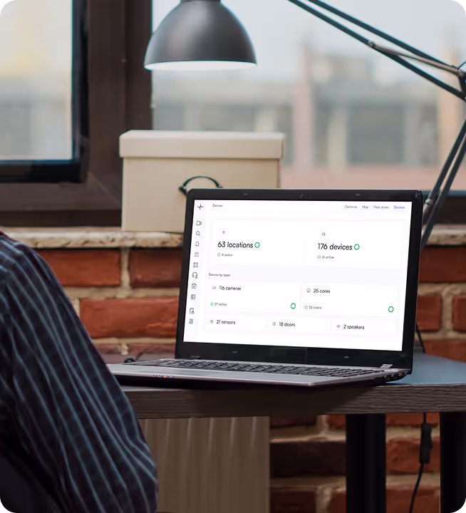 Open laptop on a table displaying a dashboard with device and location statistics in an indoor workspace.