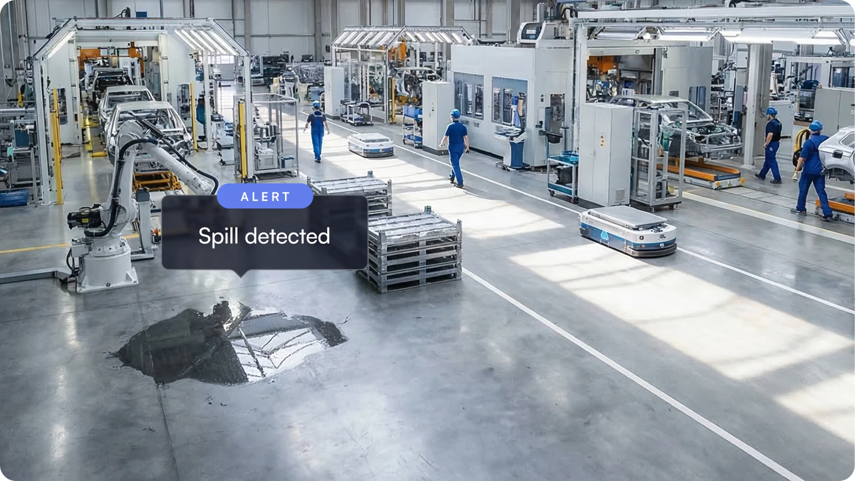 Industrial factory floor with an automated robot arm, workers, and a detected liquid spill on the concrete surface.