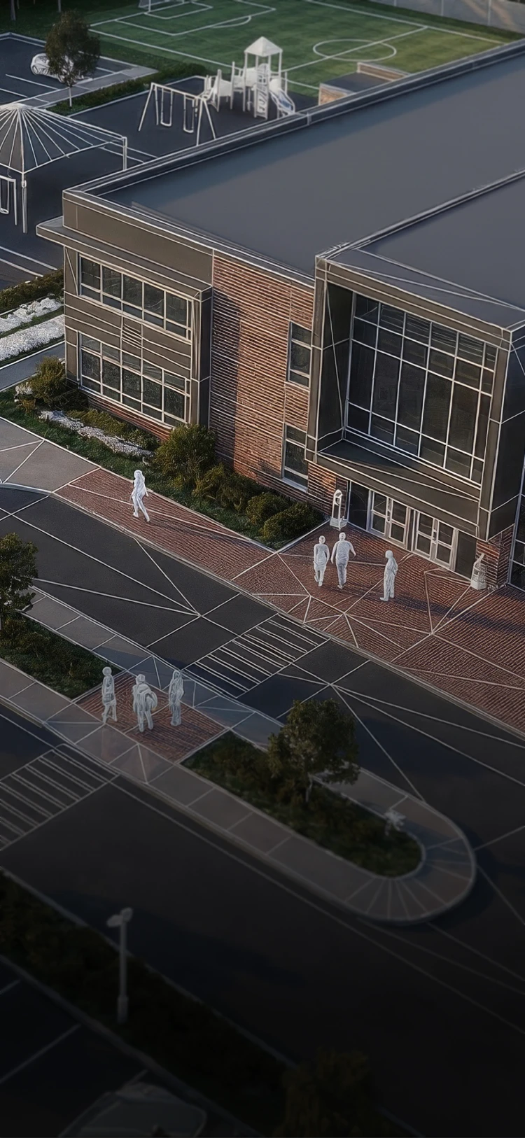 Aerial view of a modern school building with large windows and a playground with swings and a slide in the background.