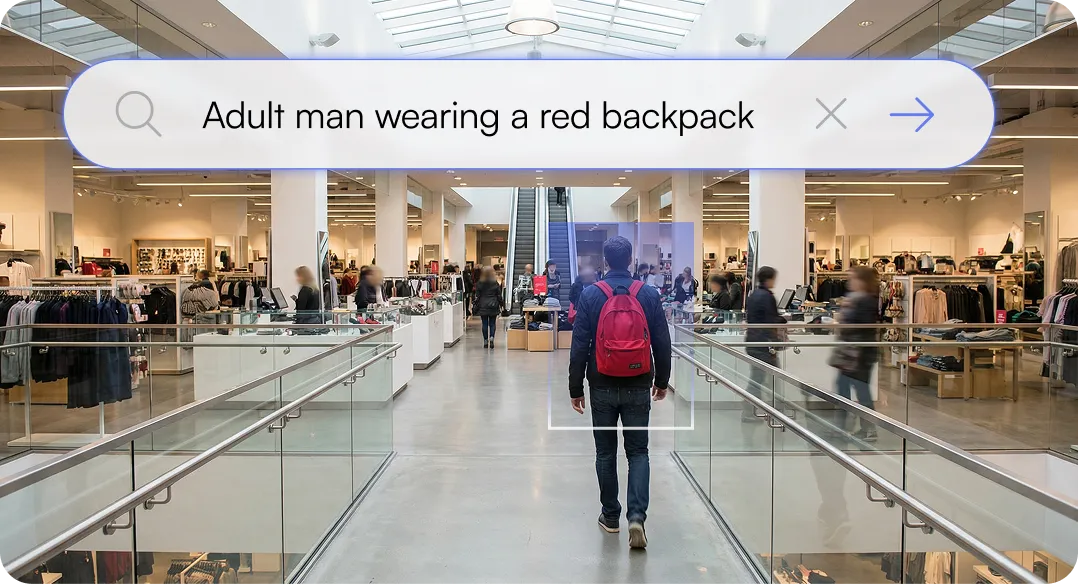 Adult man with a red backpack walking inside a modern shopping mall with clothing stores and escalators.