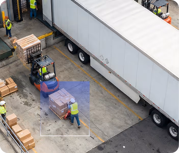Workers loading and unloading boxes using forklifts and pallet jacks beside a large white transport truck.
