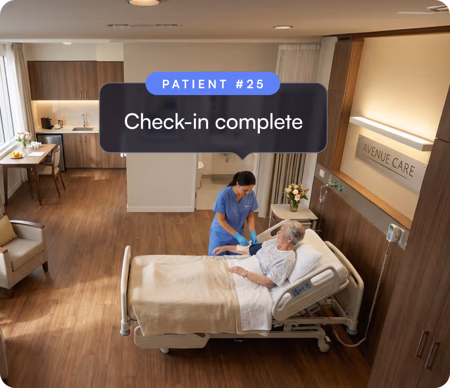 Nurse in blue scrubs attending to an elderly female patient in a hospital bed in a modern healthcare room labeled Avenue Care.