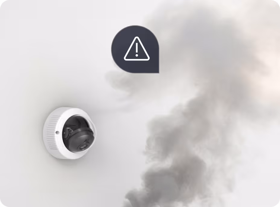 Smoke detector on a wall detecting smoke with a warning alert symbol above it.