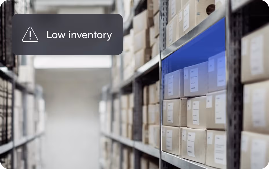 Warehouse shelves with boxes and a warning overlay saying low inventory.