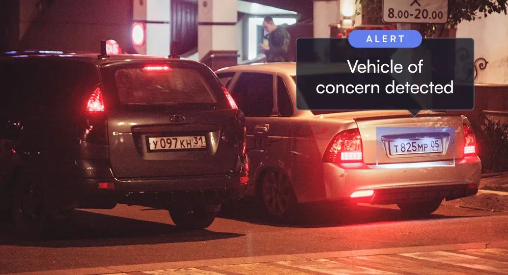 Two parked cars at night with an alert box saying vehicle of concern detected over one car.