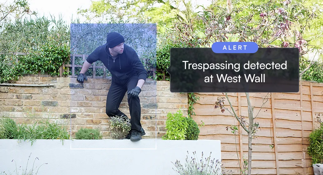 Man in black clothes climbing a garden wall with alert for trespassing detected at West Wall.