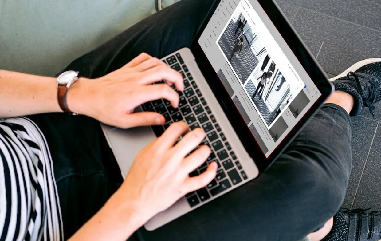 Person typing on laptop showing two black and white security camera images on screen.