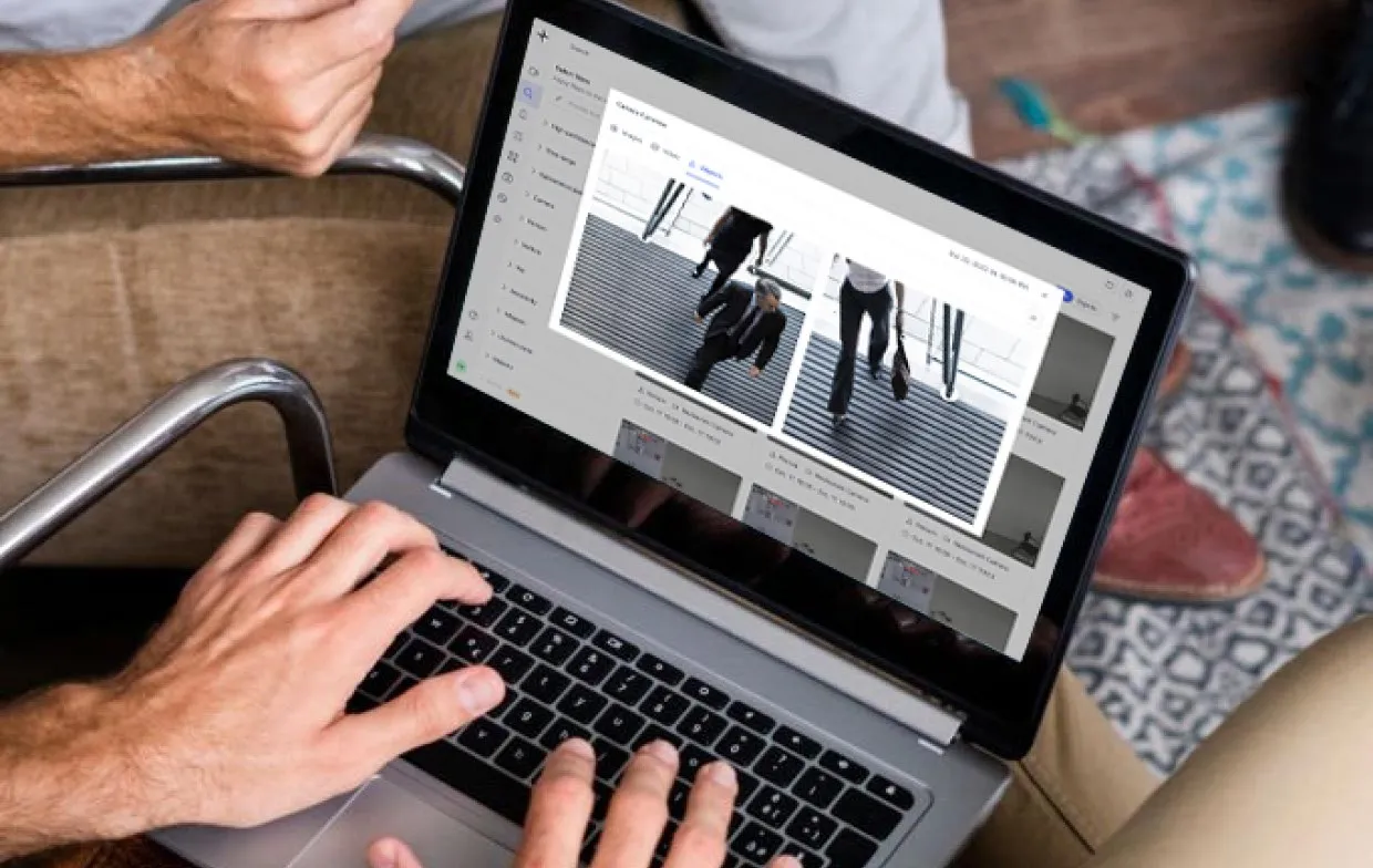 Person editing or reviewing surveillance video footage of people walking on a laptop screen.