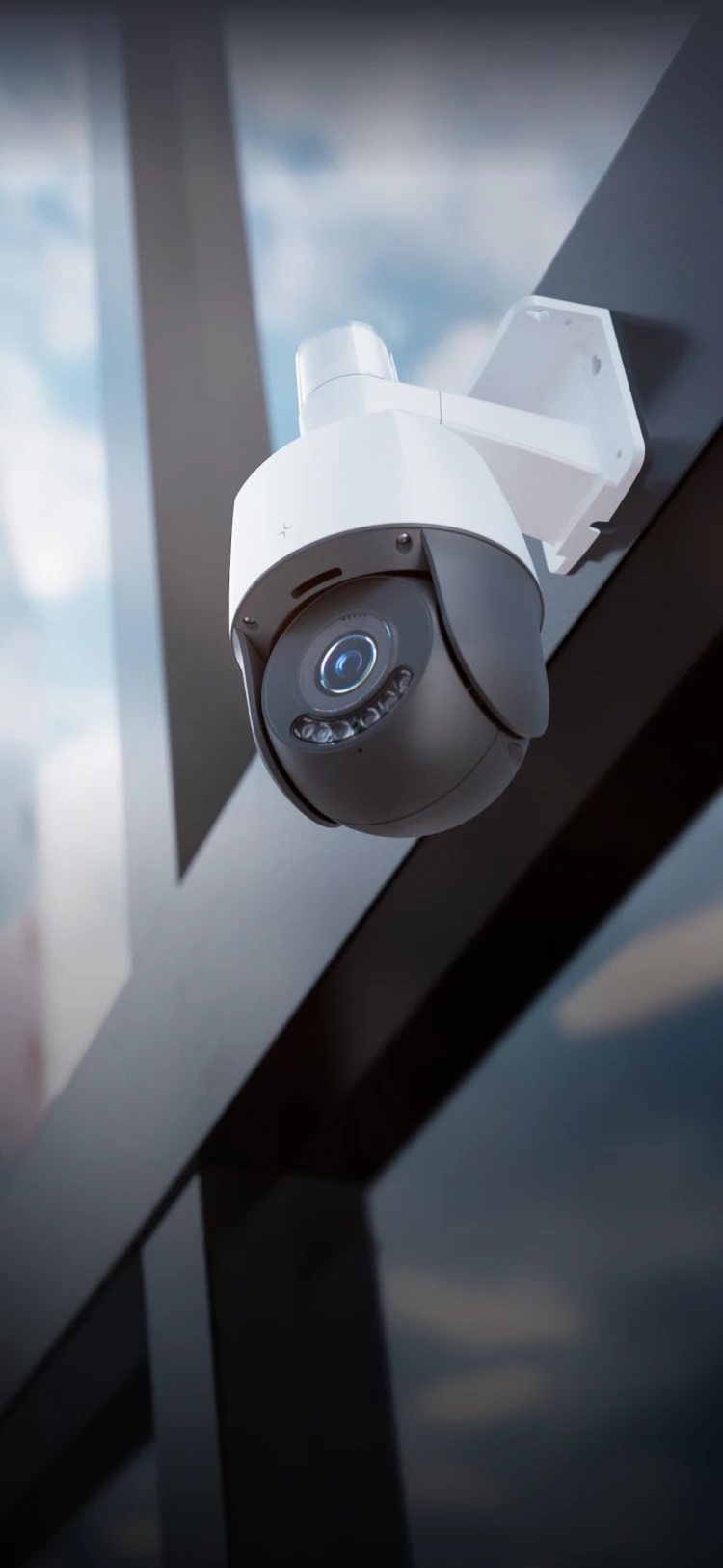 White and black outdoor security camera mounted on a modern glass building wall.