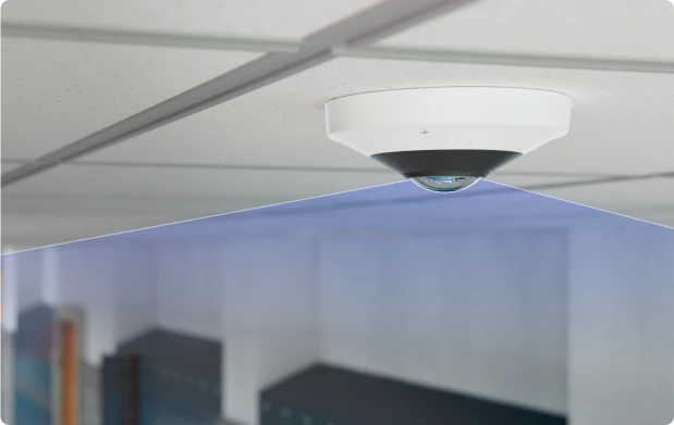 Dome security camera mounted on a ceiling with a blue light reflecting below it.