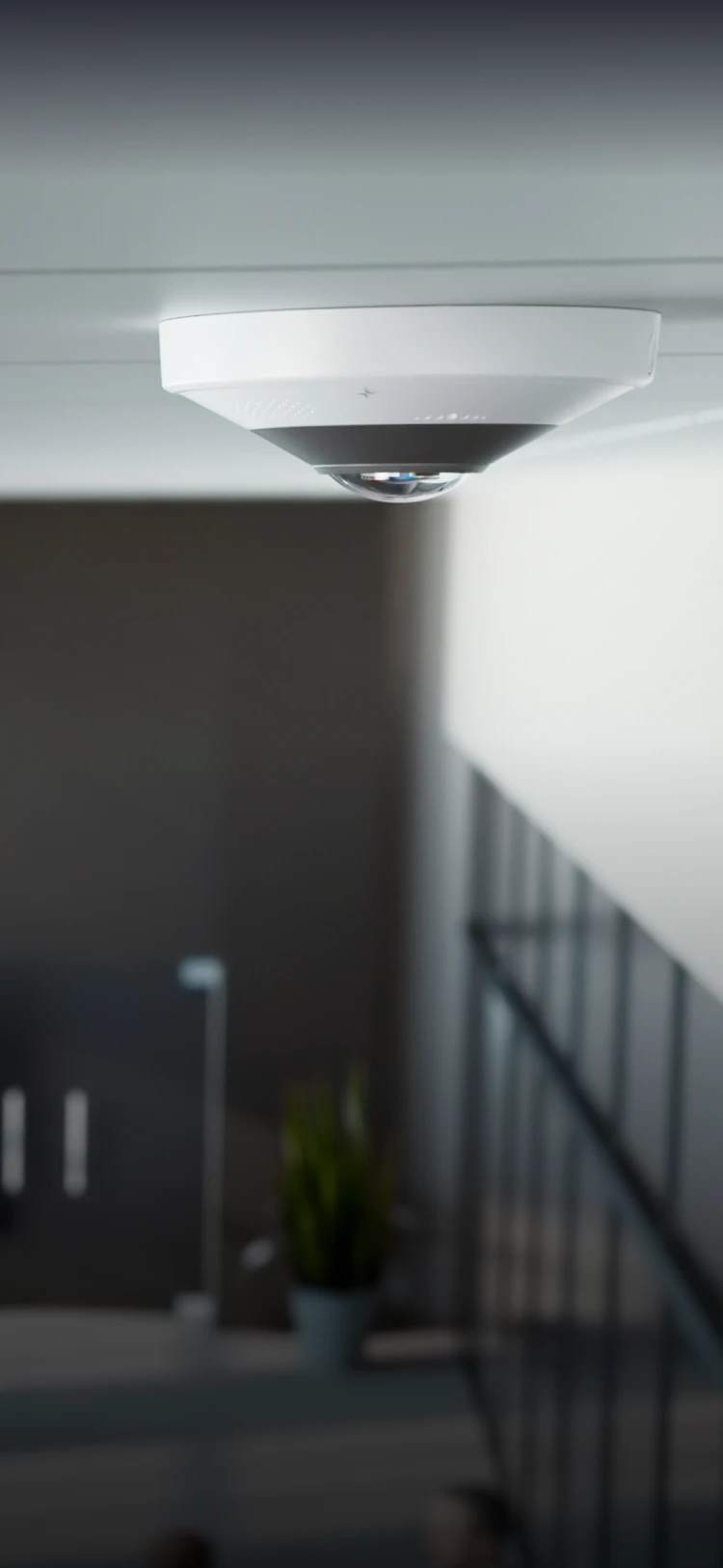 Ceiling-mounted security camera with a fisheye lens in a modern indoor space.