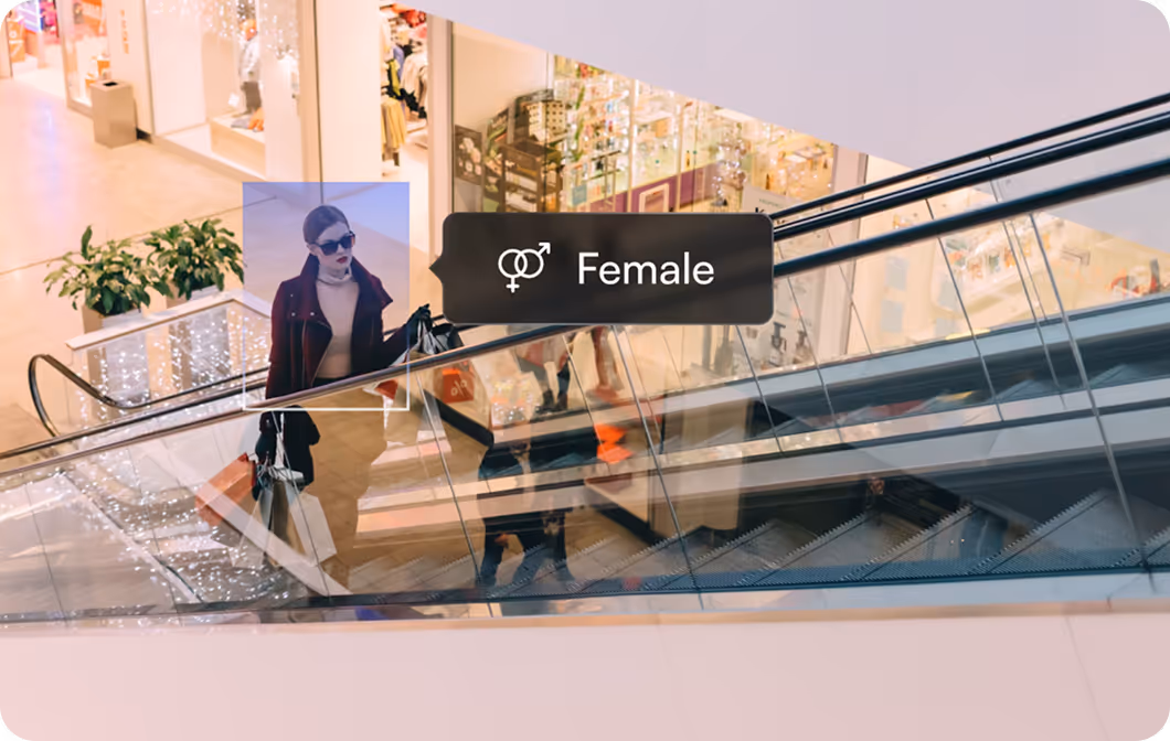 Woman carrying shopping bags on an escalator with a label identifying her as female.