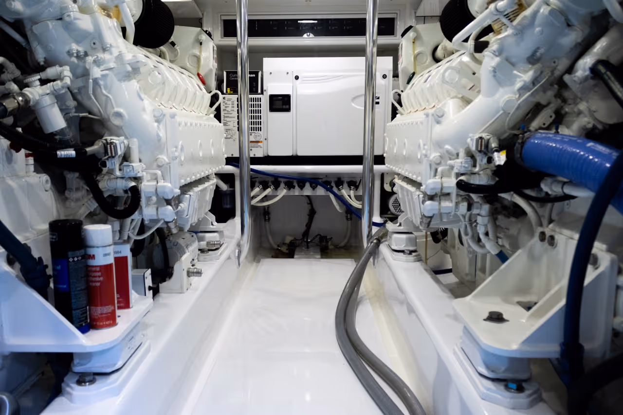 Clean, white marine engine room with two large engines and a white control unit in the center.