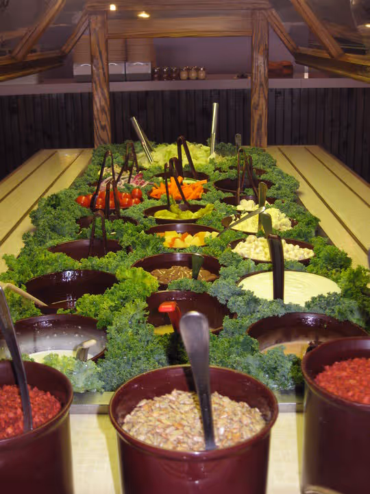 A colorful salad bar featuring a variety of fresh vegetables, fruits, and toppings.