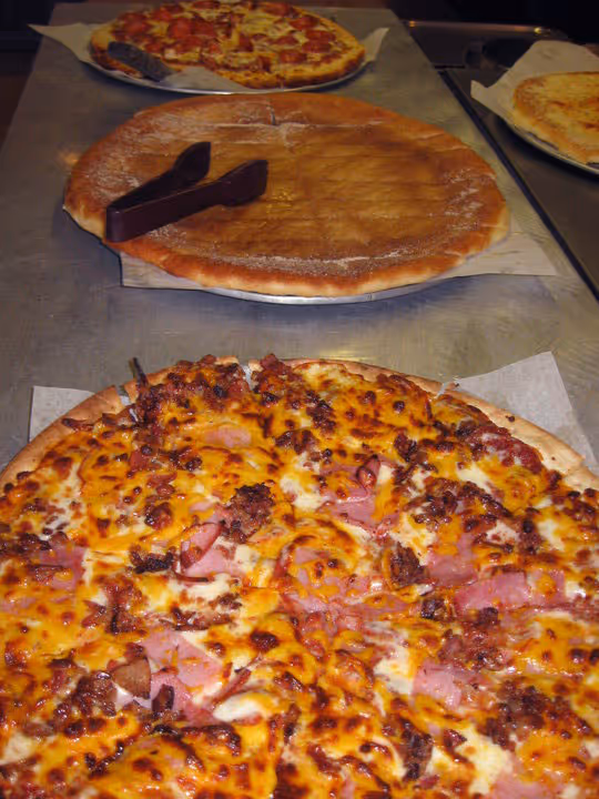 Assorted pizzas on a metal counter.