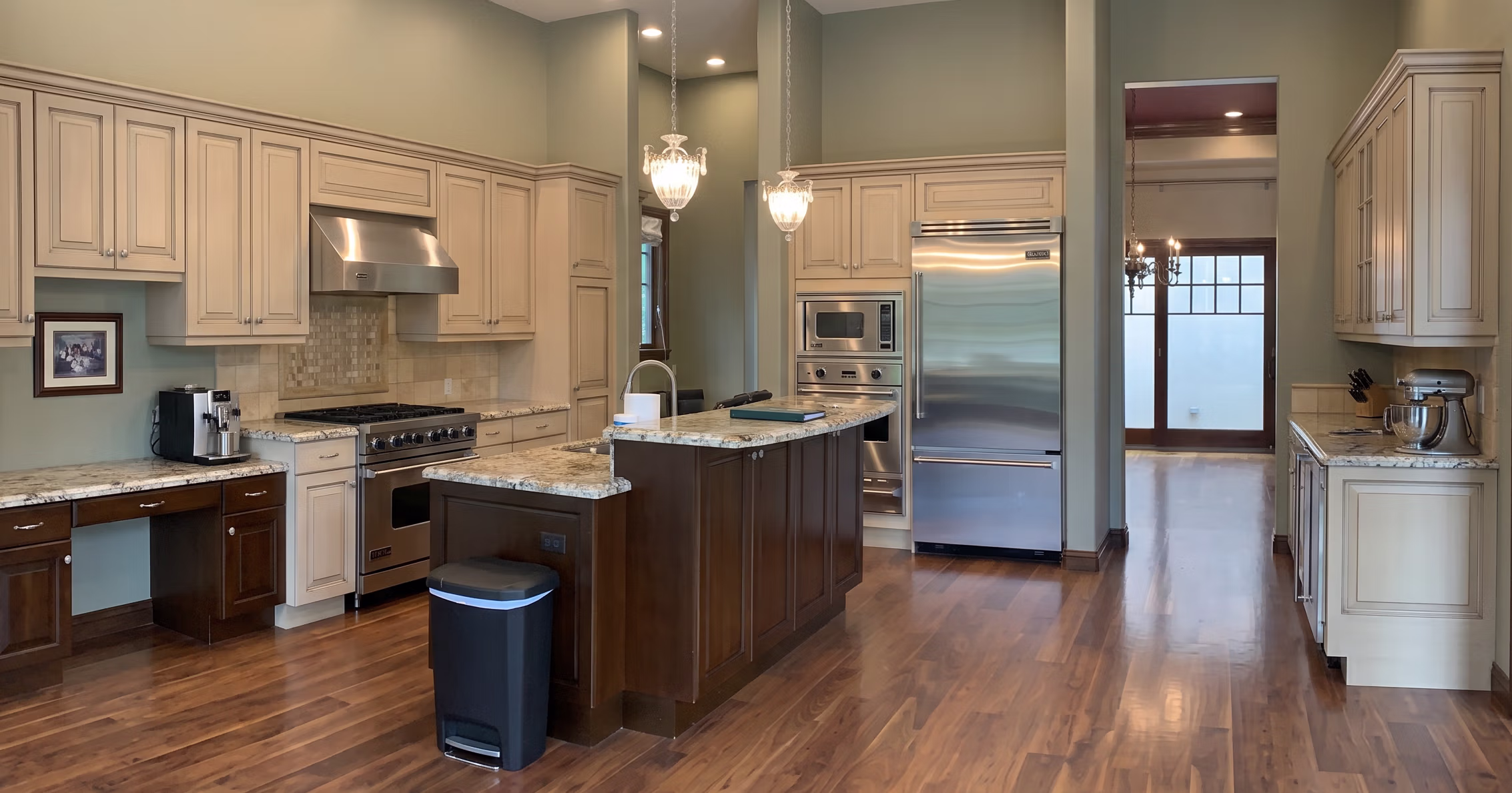 Spacious kitchen with island, granite counters, stainless steel appliances, hardwood floors, and pendant lights.