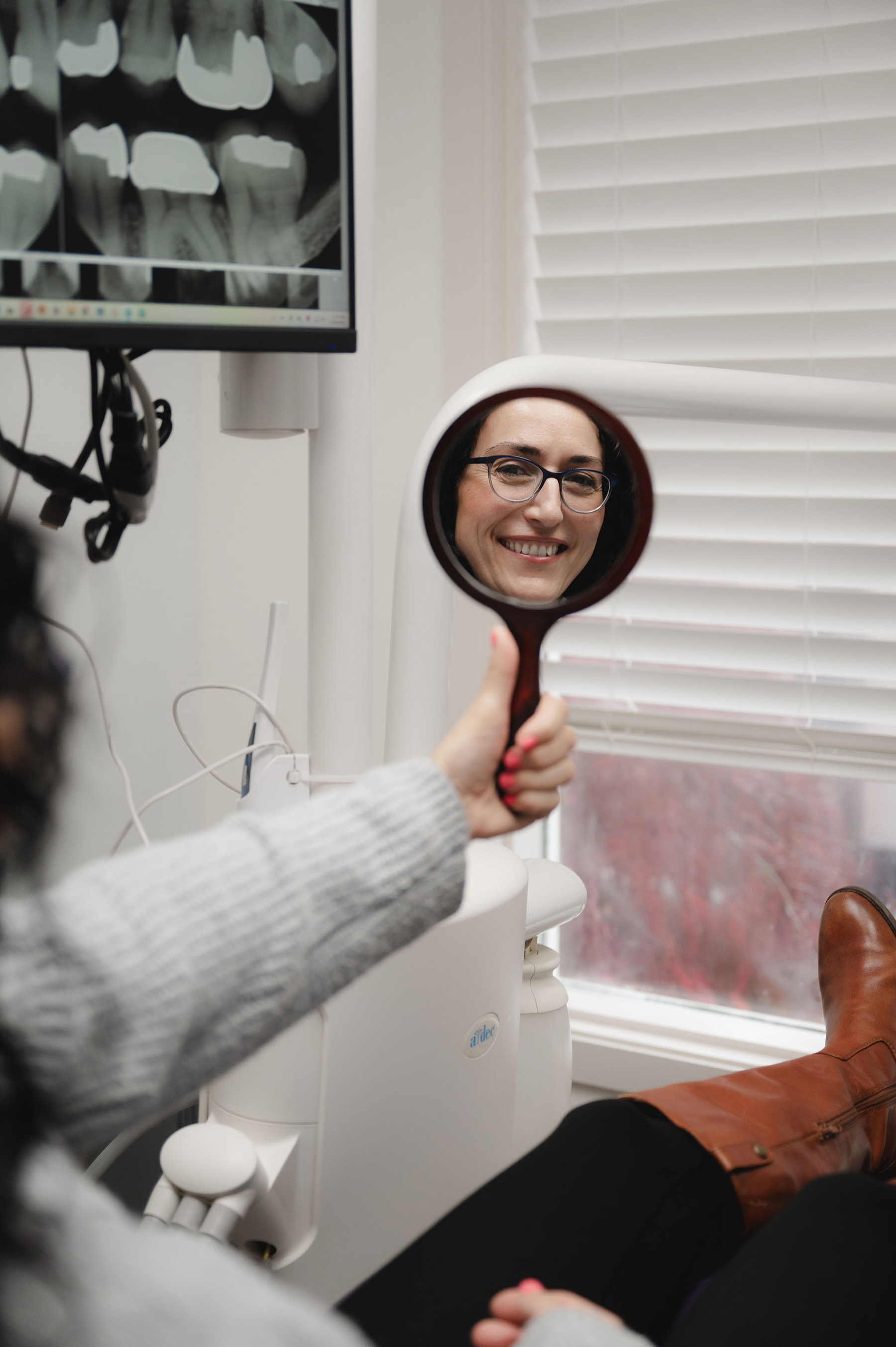Close-up of a smiling woman with light wavy hair wearing a white knitted sweater.