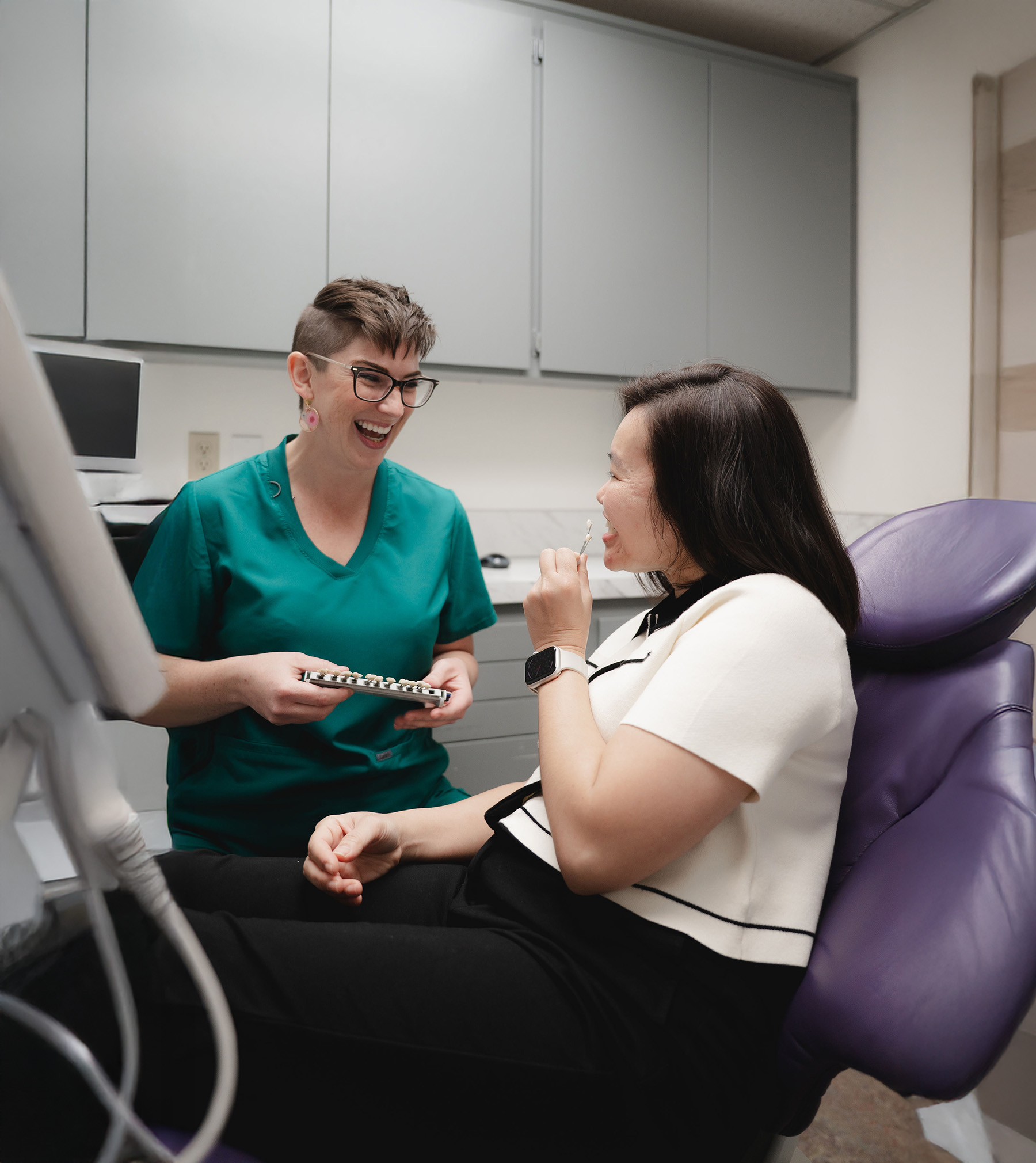 Wooden toothbrush with soft bristles on a white speckled surface next to a dental shade guide.