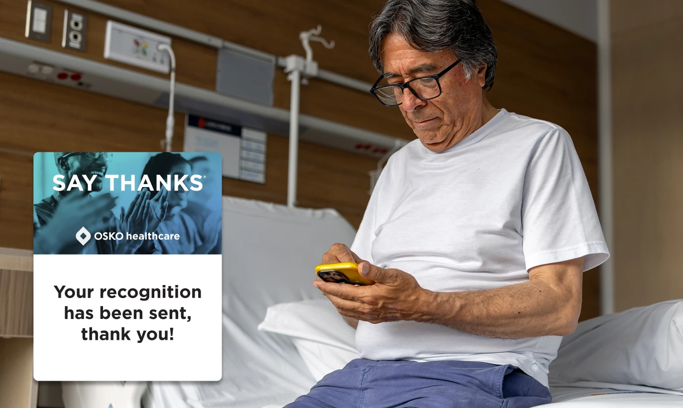 Un professionnel de santé en blouse bleue regardant son smartphone dans un couloir d'hôpital, avec un message en surimpression indiquant : « DITES MERCI. OSKO healthcare. Votre message de remerciement a été envoyé, merci ! »