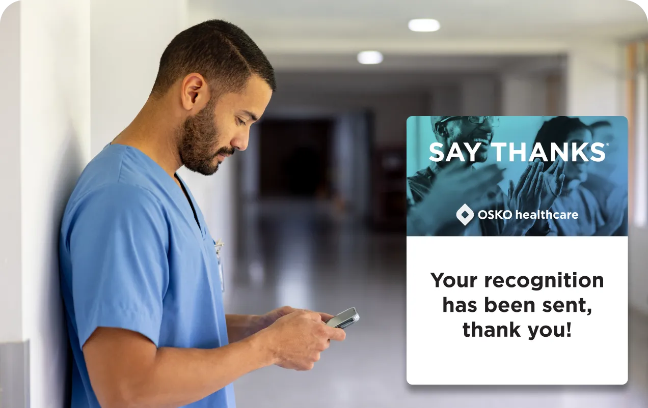 Healthcare worker in blue scrubs looking at a smartphone in a hospital corridor, with a message overlay saying 'SAY THANKS. OSKO healthcare. Your recognition has been sent, thank you!'