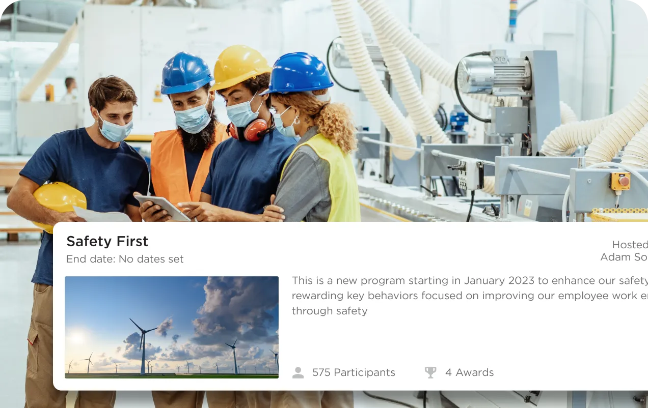 Four factory workers wearing safety helmets and masks reviewing a tablet in a manufacturing facility.
