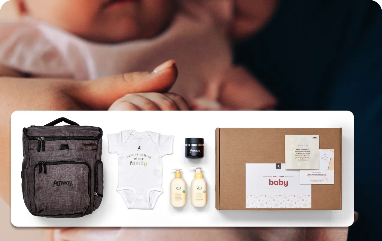 Gift set including Amway backpack, baby onesie with 'A newest member of our family' text, skincare products, and a box labeled 'Welcome baby'.