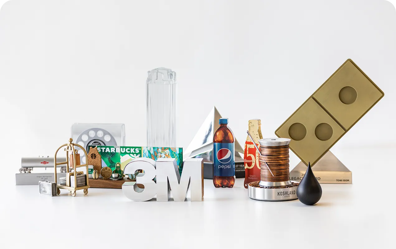 A collection of various awards and branded items including a Starbucks card, a Pepsi bottle, a 3M logo, and several trophies and plaques on a white surface.