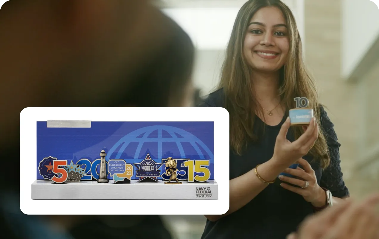 Smiling woman holding a small blue award with the number 10, next to a display stand showcasing various awards and trophies.