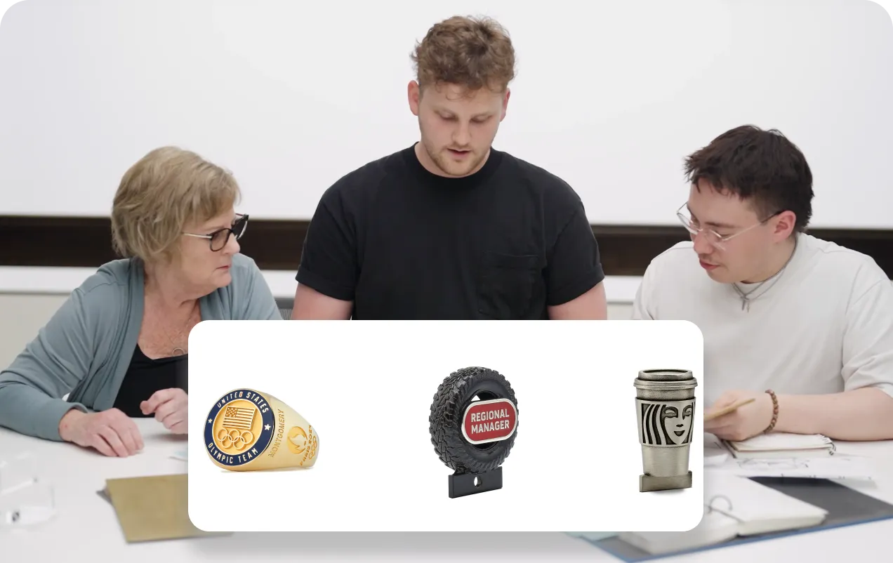 Three people sitting at a table with papers and notebooks, viewing three different award pins: a United States Olympic Team gold ring pin, a tire-shaped Regional Manager pin, and a coffee cup pin with a face logo.