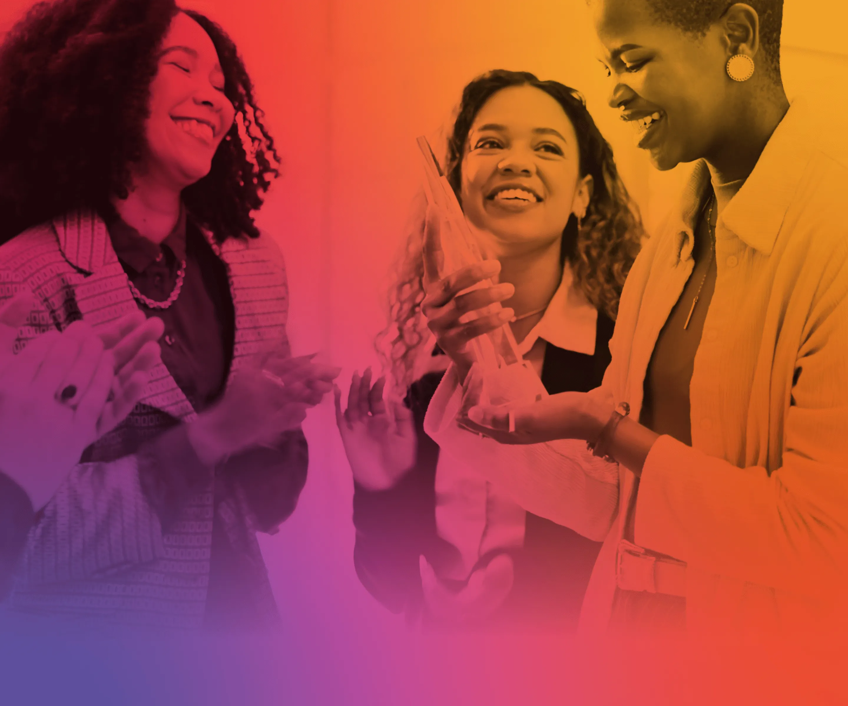 Three women smiling and celebrating, one holding a clear trophy in her hands.