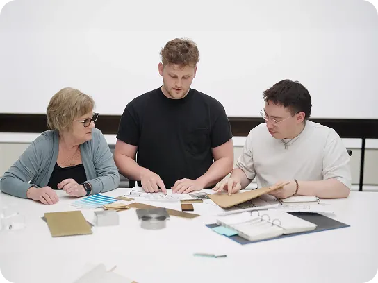 Three people sitting at a table reviewing documents and samples together.