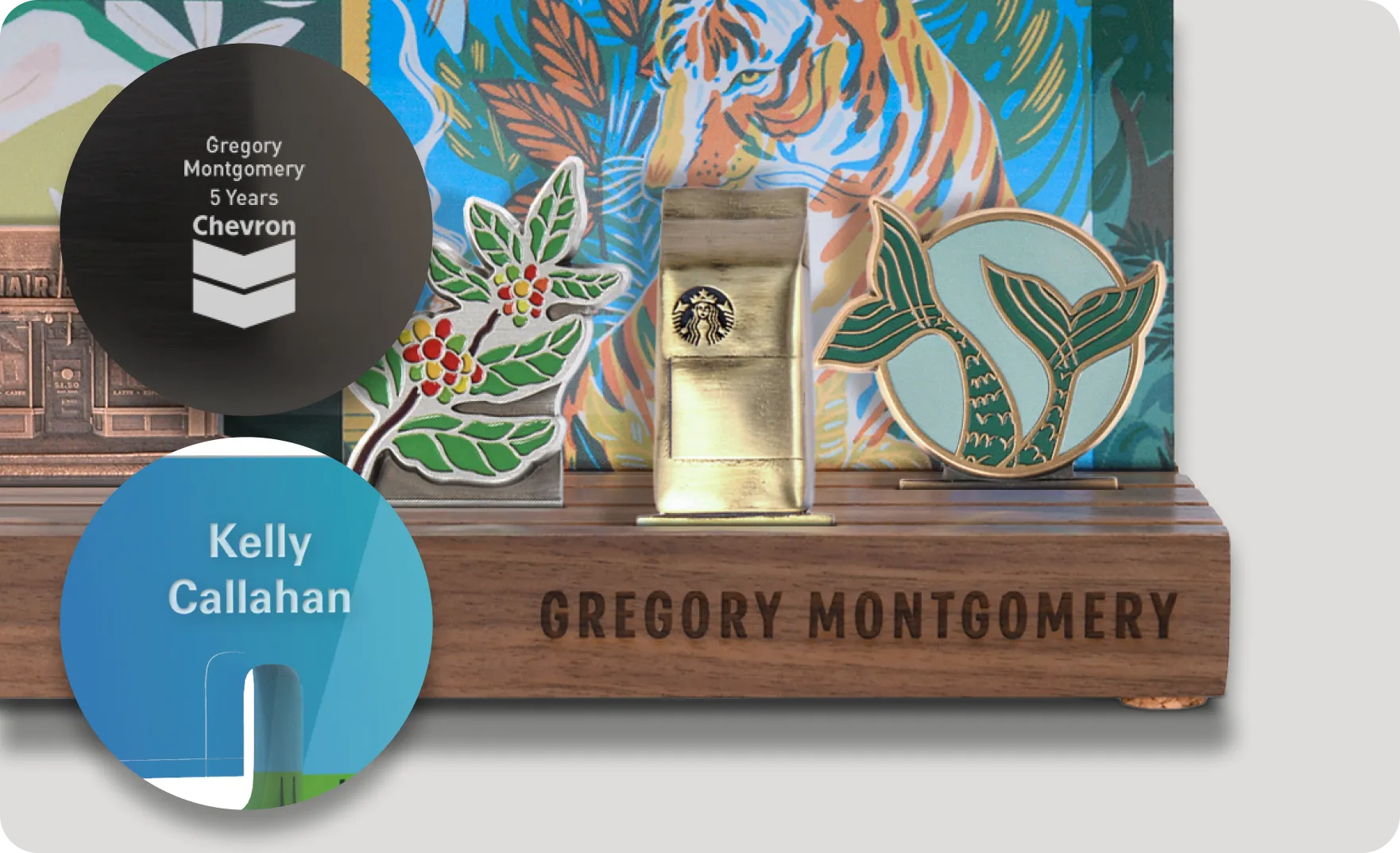 Custom awards display with a wooden base engraved 'Gregory Montgomery' featuring a gold Starbucks bag trophy and colorful enamel pins of coffee plant and a mermaid tail.