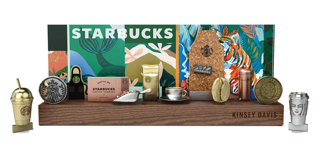 Starbucks-themed miniature display with branded items including a coffee cup, coffee bean bag, a scoop, a coffee cup and saucer, a corkboard with '2022 Starbucks' plaque, and various Starbucks logos on a wooden base.