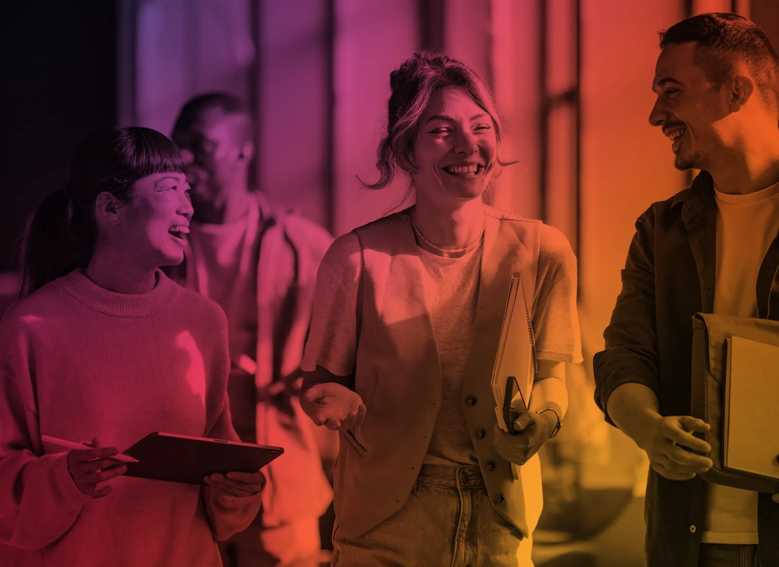 Quatre jeunes adultes d'horizons différents qui marchent et rient ensemble, un cahier et des chemises à la main.