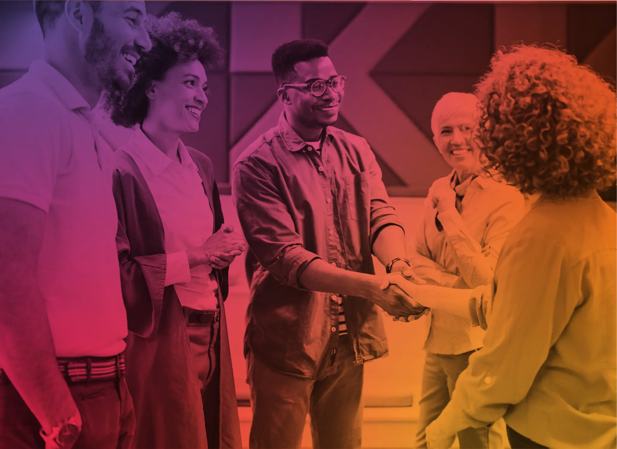 Five diverse people smiling and shaking hands in a modern office setting.