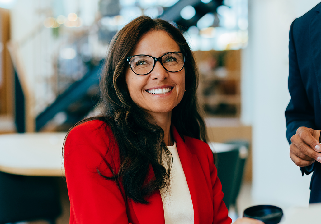 A professional woman sitting down and smiling off in the distance.