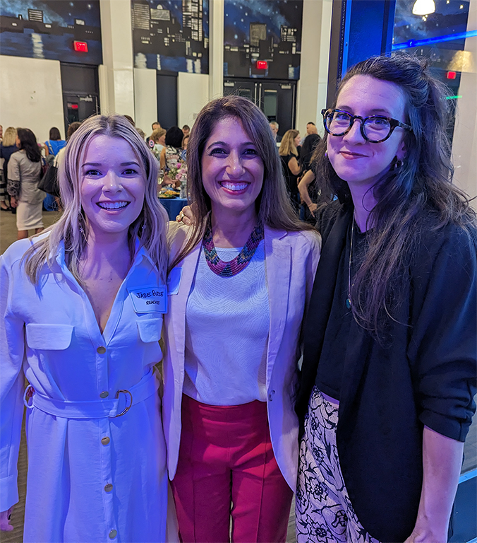 A group of three women in professional clothing lined up and smiling at the camera.