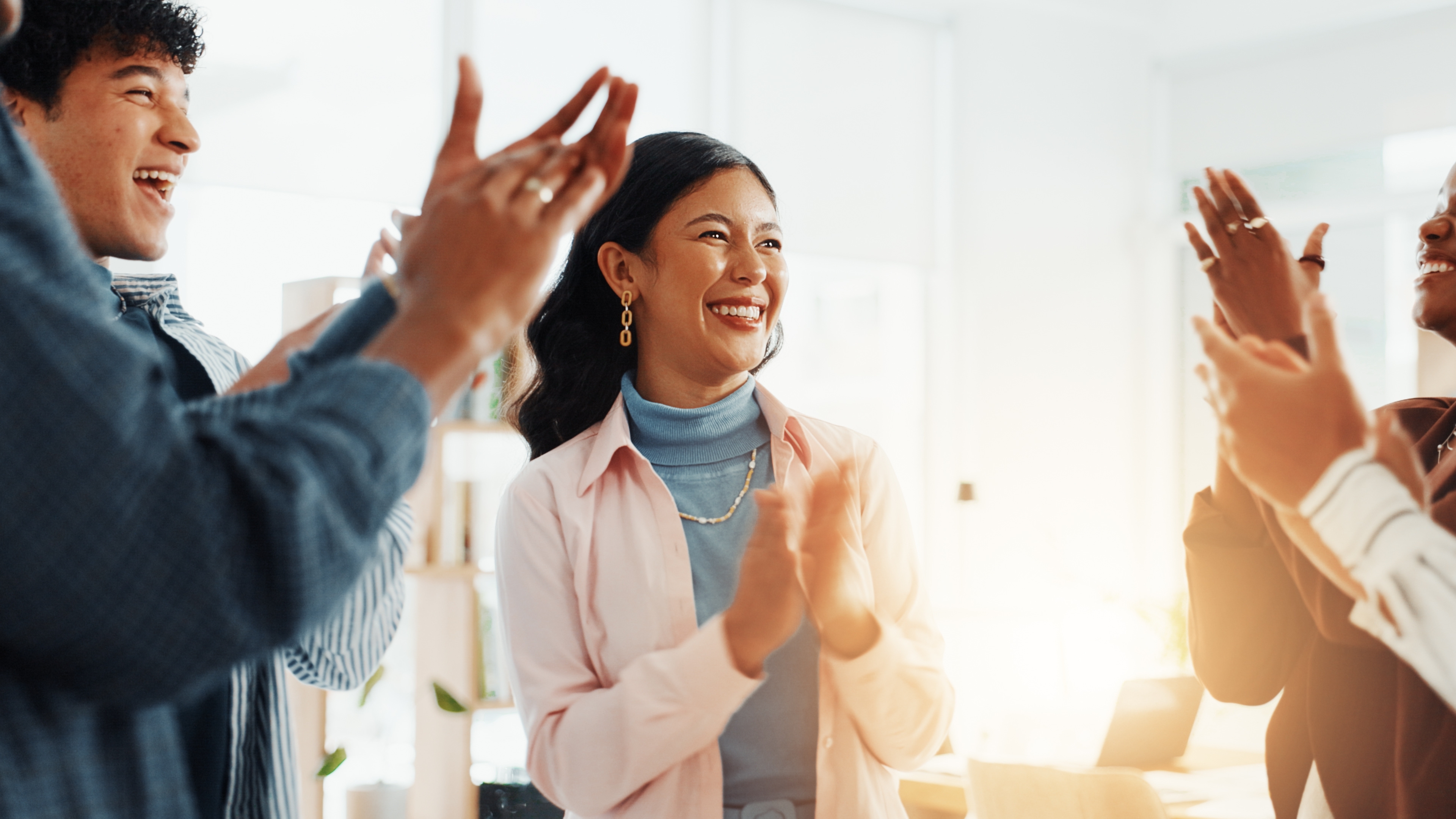 Group of professionals smiling at each other and clapping.