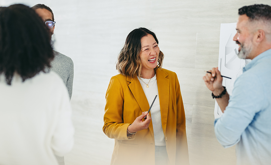 A group of professionals in a meeting setting, smiling at each other.