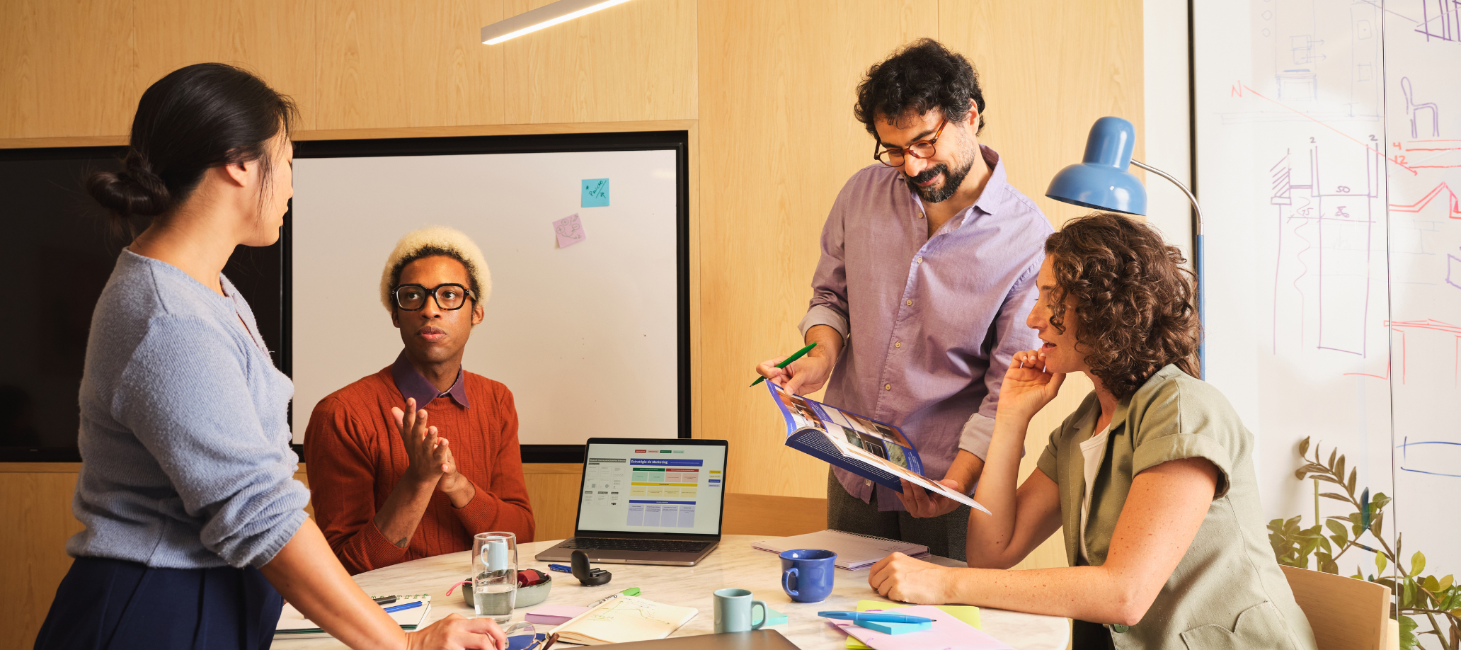 Group of four professionals around a desk talking and collaborating.