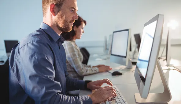 Man and woman working on desktop computers in an office setting.