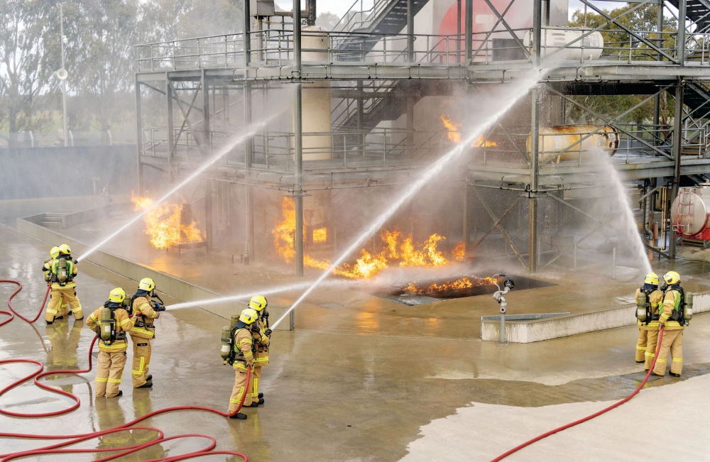 Firefighters in a training scenario hosing down a fire