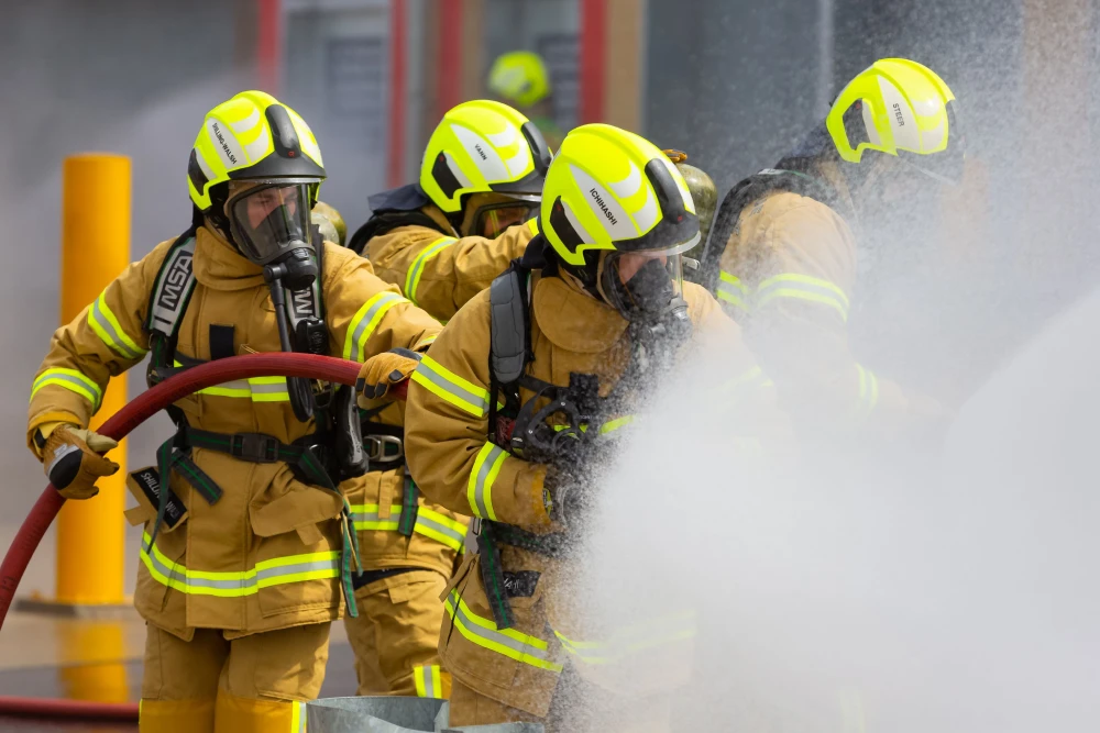 A group of firefighters holding a firehose spraying water