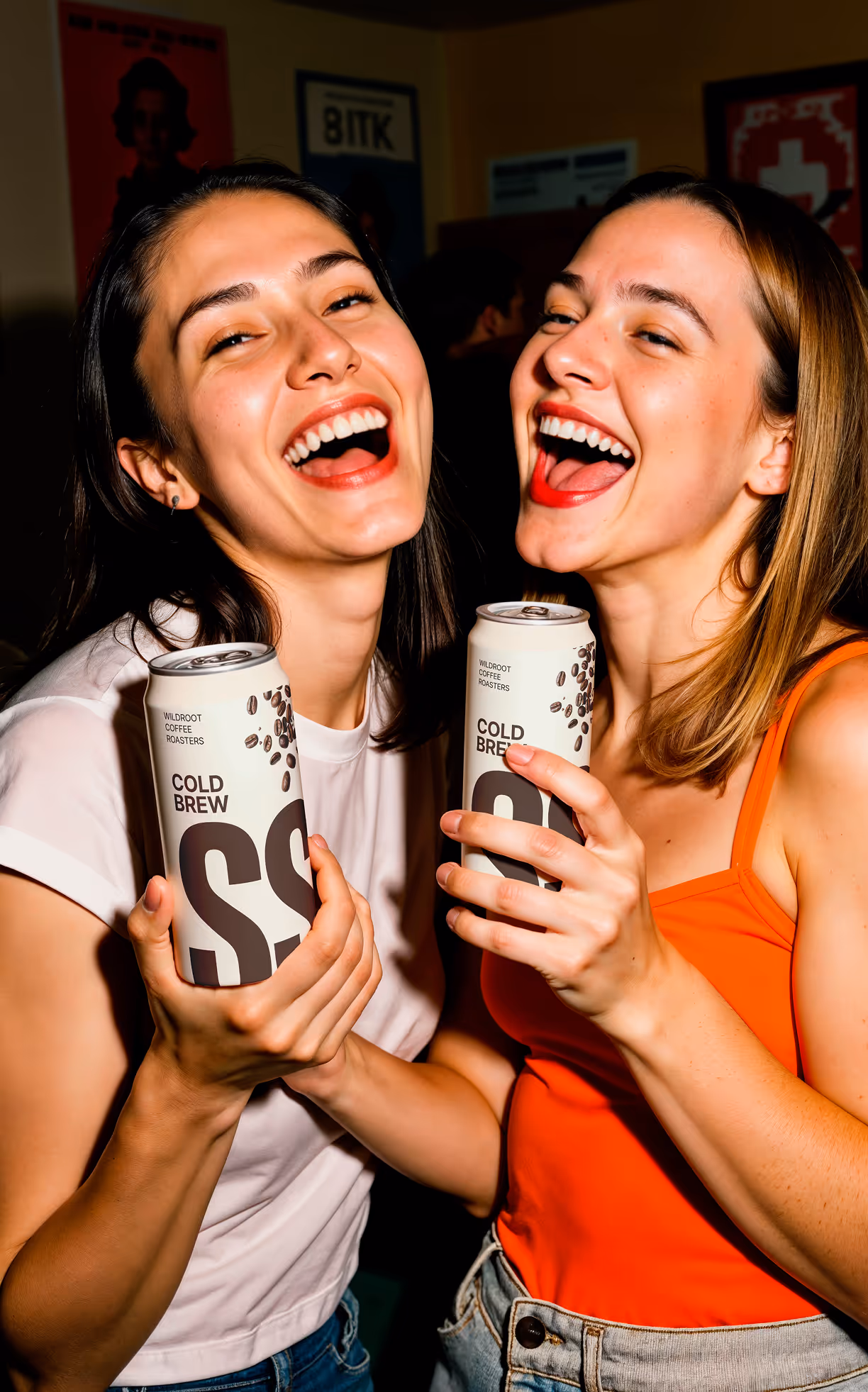 two women smiling and holding stone sip cold brew cans together