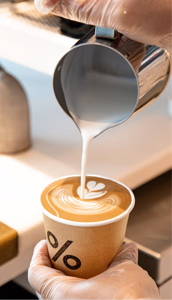 Creamy milk being poured into coffee, emphasizing smooth flavor and craft preparation.
