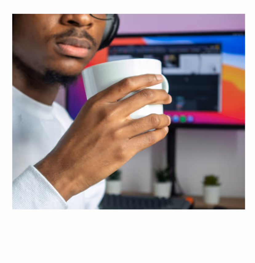 Person holding a takeaway coffee cup in a modern workspace environment.