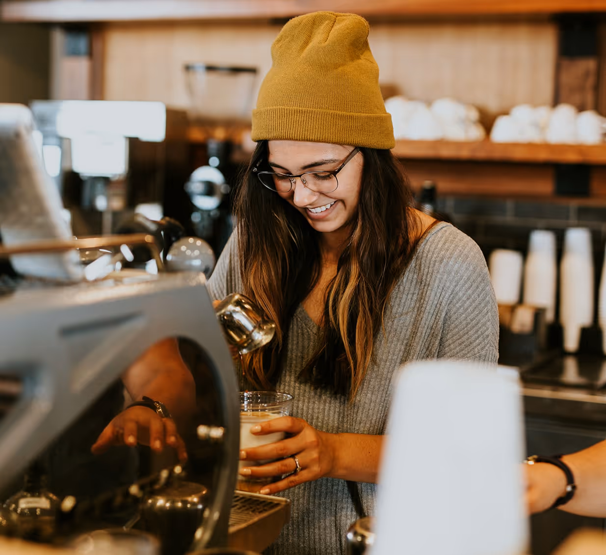 Barista preparing coffee behind the counter in a modern café setting.