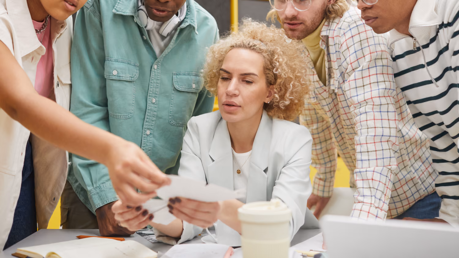 A team gathered around a table reviewing and discussing papers in a collaborative meeting.