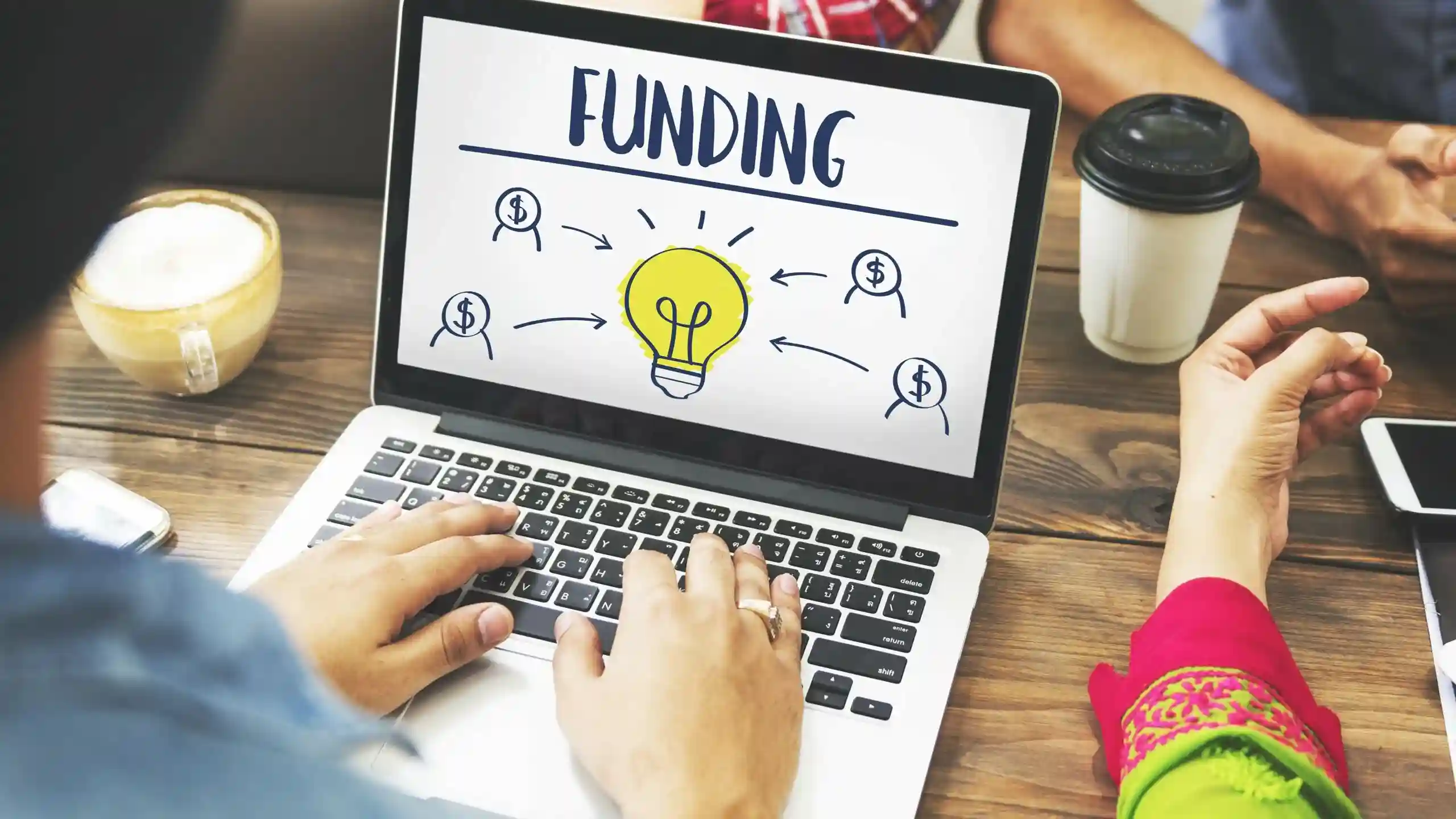 A person types on a laptop that displays the word